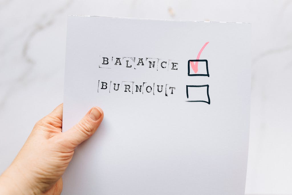 A hand holding a checklist highlighting the choice of balance over burnout, emphasizing mental health awareness.